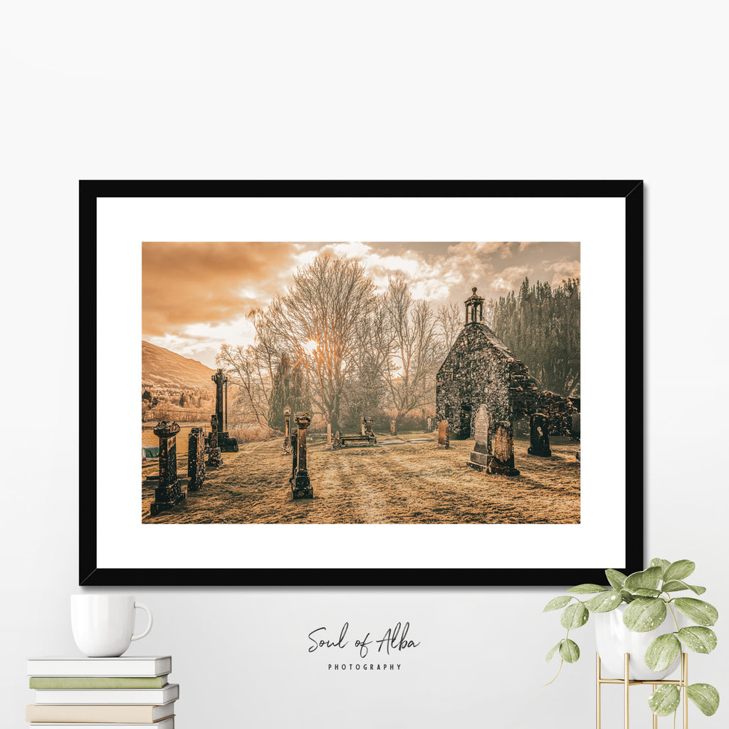 Framed fine art print of Balquhidder Kirk displayed in a modern interior, showcasing the historic church and graveyard in Perthshire.