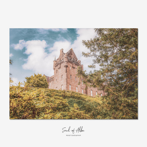 Fine art photograph of Brodick Castle on the Isle of Arran, Scotland, rising above woodland and framed by mature trees beneath a soft Scottish sky.