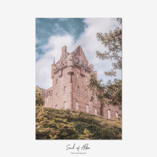 Portrait fine art photograph of Brodick Castle on the Isle of Arran, featuring its historic sandstone tower framed by mature trees and a soft blue Scottish sky.