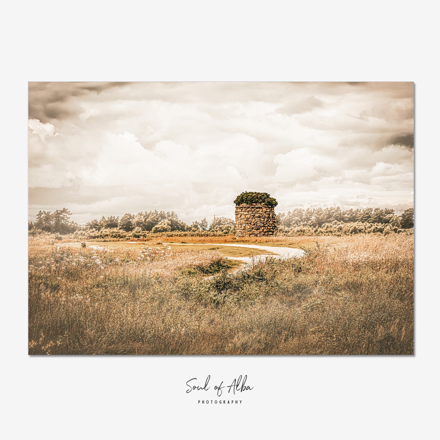Memorial cairn standing on Culloden Battlefield near Inverness, Scotland, beneath dramatic clouds and golden light.